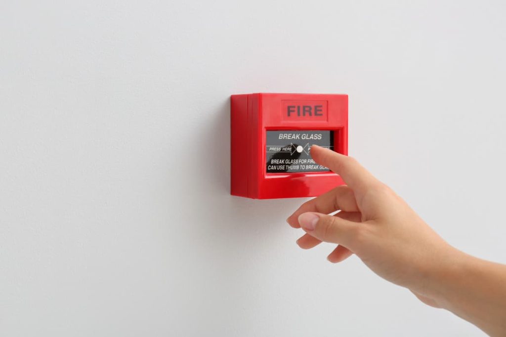 hand reaching out to fire alarm